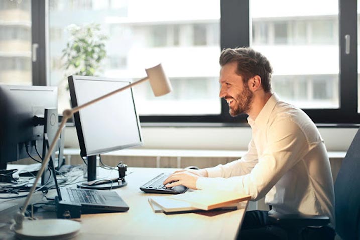 man smiling while using his computer